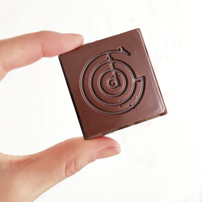 Someone Hold a Piece of Good Chocolate with an embossed logo design.