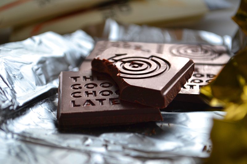 Pieces of The Good Chocolate with the logo embossed, resting on a foil wrapper.