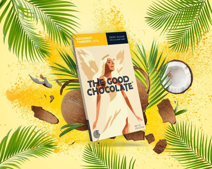 A package of The Good Chocolate's Coconut Turmeric 65% Zero Sugar dark chocolate bar is displayed against a vibrant yellow background with tropical elements. The background includes palm leaves, coconut pieces, and turmeric powder, emphasizing the exotic flavors of the chocolate.